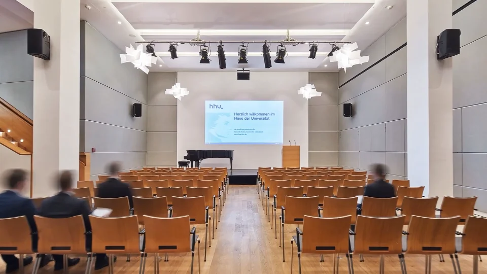 Blick in den leeren Veranstaltungssaal mit Stuhlreihen, Bühne und Flügel