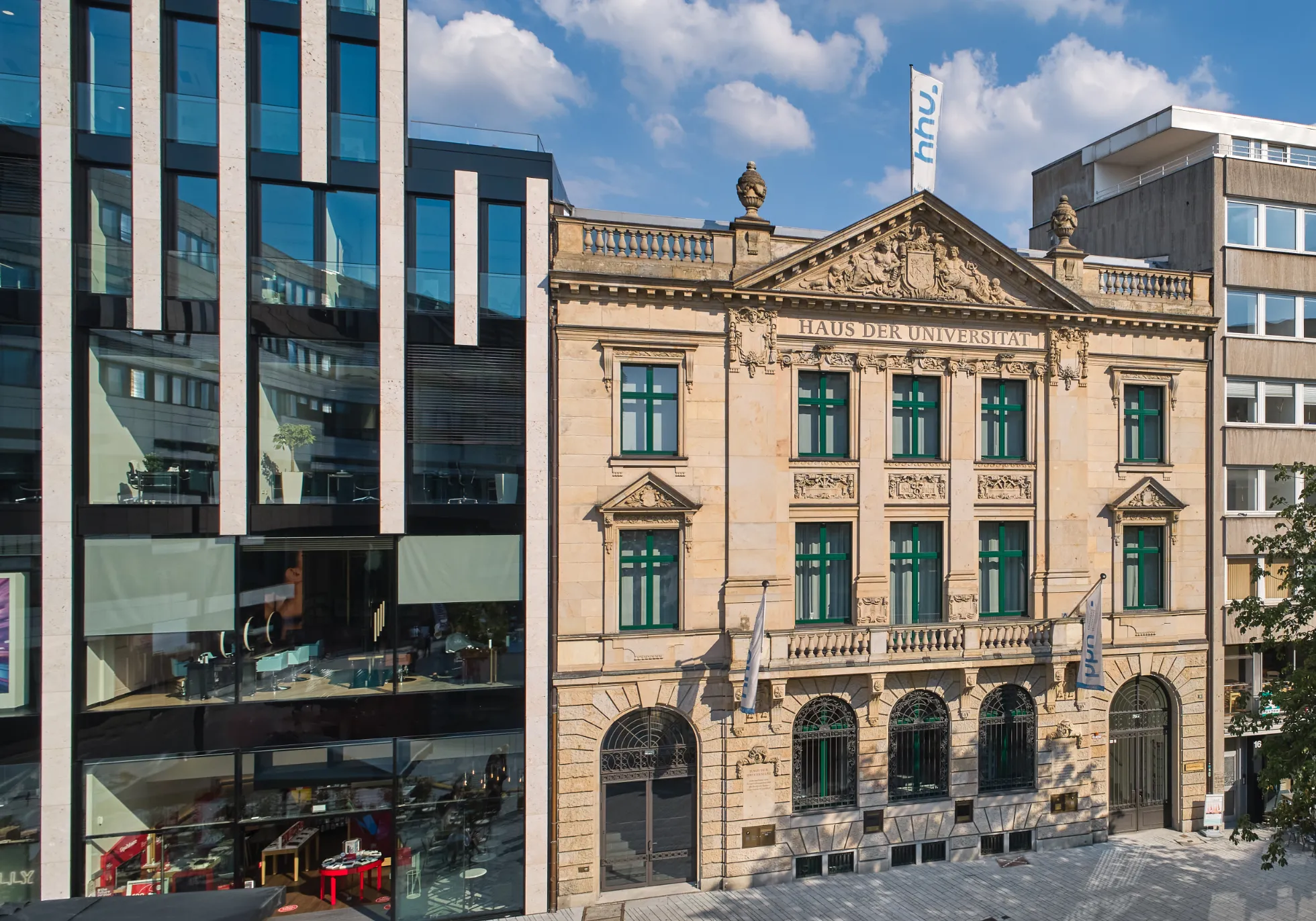 Historische Sandsteinfassade des Haus der Universität neben moderner Glasarchitektur
